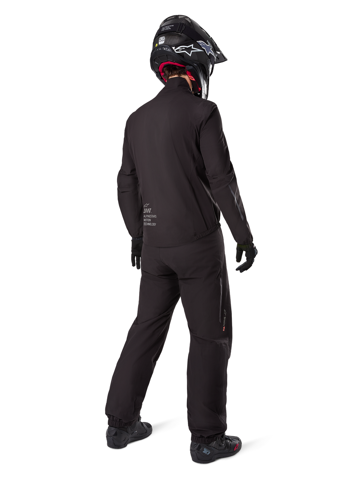 Motorradfahrer in der Rückansicht mit der schwarzen Amt-8 Stretch Drystar® XF Hose und passender Jacke, komplettes Adventure-Touring-Outfit mit schwarzem Helm und Stiefeln, technische wasserdichte und dehnbare Ausrüstung für Langstrecken-Motorradtouren