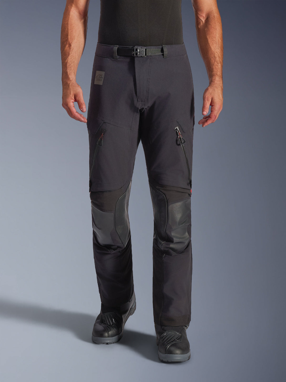 Alpinestars Halo Pro Drystar® XF Laminated Pants in Black Dark Shadow, adventure motorcycle pants, front view on model featuring magnetic waist buckle, zippered thigh vents, and reinforced leather knee patches, paired with black riding boots.