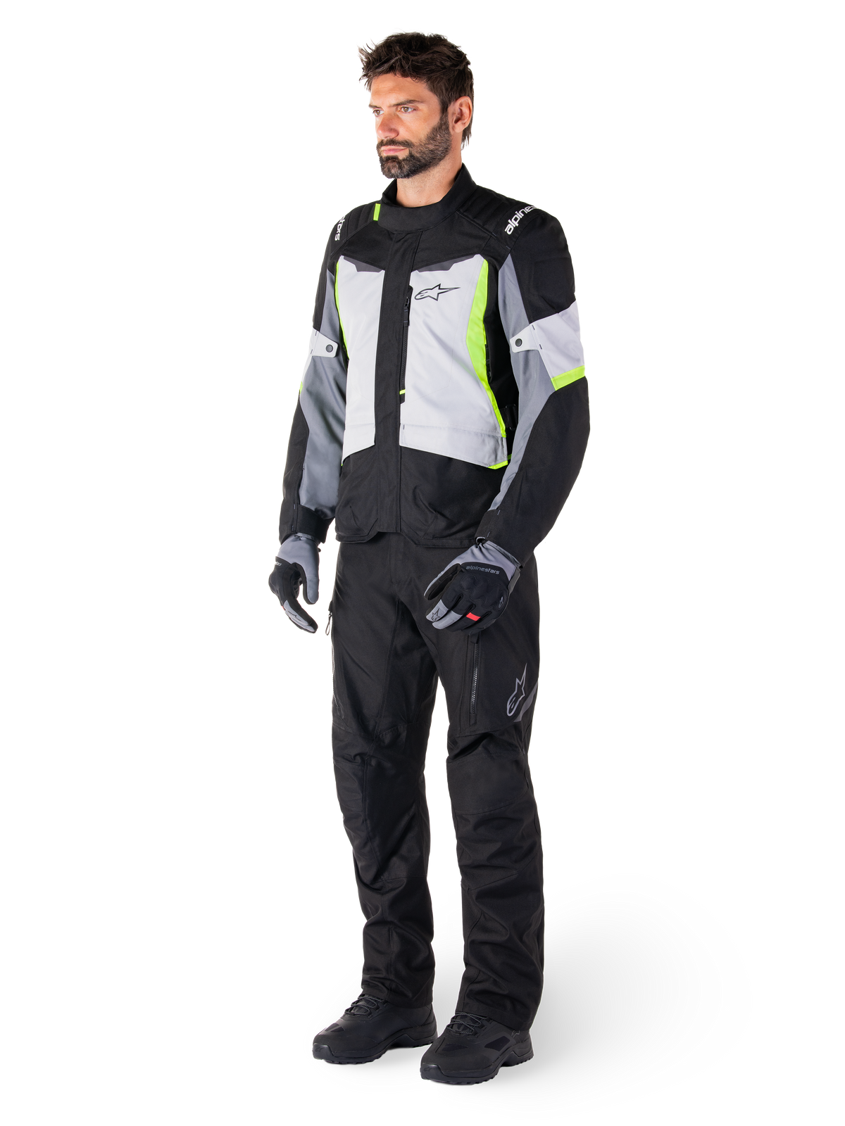 Alpinestars ST-1 Waterproof Pants, Black, worn by a male model with a grey and neon yellow touring jacket, black gloves and boots, featuring a textile design with the Alpinestars logo on the thigh, designed for all-weather adventure touring