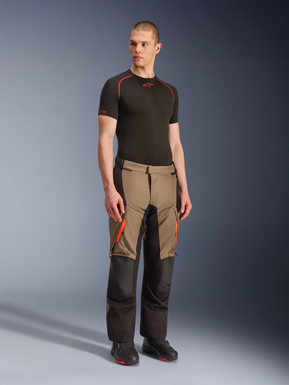 Alpinestars Andes V4 Drystar® Pants, Motorcycle Adventure Touring Pants, Walnut Black with orange accents, worn by model with black short-sleeve base layer and black boots, featuring reinforced textile panels and cargo pockets, rugged design for all-weather riding