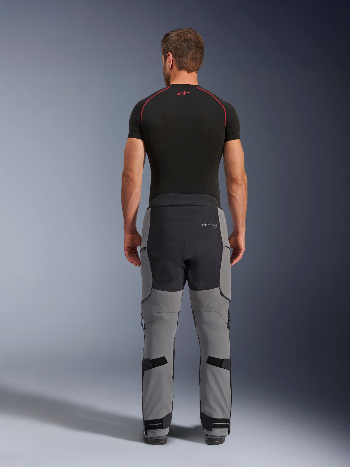 Alpinestars Andes Pro Drystar® XF Pants, Adventure Motorcycle Pants, Dark Gray and Black, rear view showing gray and black paneled construction, worn with a black base layer, featuring reinforced seat and calf adjustment straps for touring.