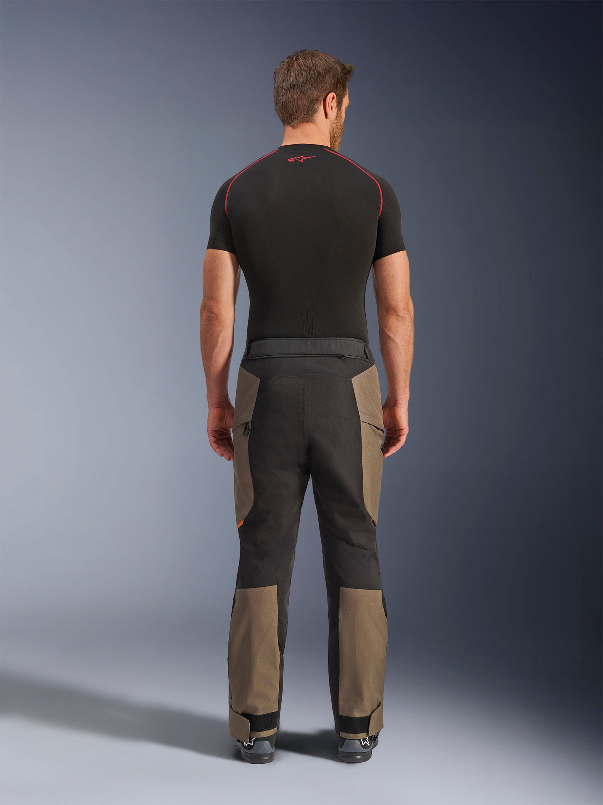 Alpinestars Cusco Drystar® Hose, Adventure-Motorradhose, Walnut Black, Rückansicht mit braunen und schwarzen Einsätzen, strapazierfähige Ripstop-Konstruktion, getragen mit einem schwarzen Base-Layer-Shirt