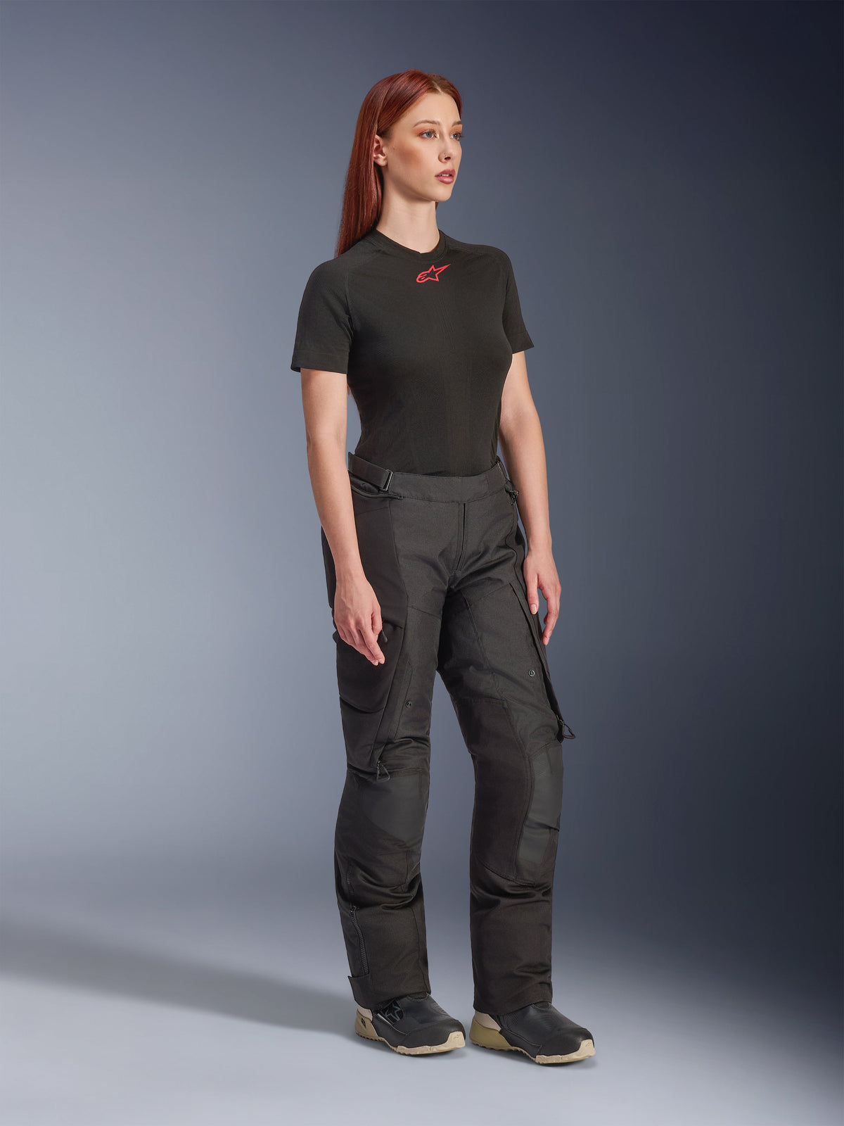 Alpinestars Stella Andes V4 Drystar® Hose, Damen-Motorradhose, Schwarz, getragen mit einem schwarzen Kurzarm-T-Shirt mit rotem Logo und technischen Schuhen, Adventure-Touring-Design mit verstärkten Einsätzen und Belüftungsreißverschlüssen, Dreiviertelansicht in voller Länge
