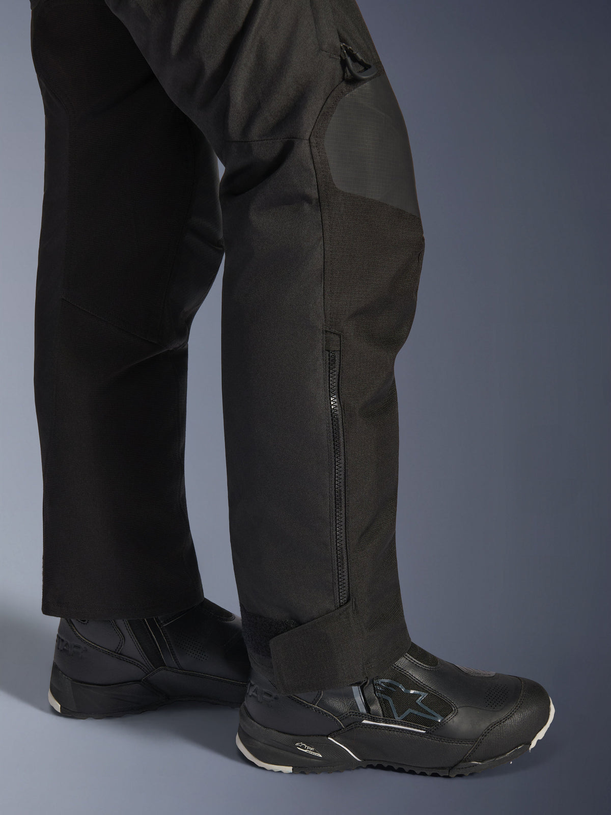 Alpinestars Stella Andes V4 Drystar® Hose, Motorradhose für Damen, Schwarz, Nahaufnahme des Unterschenkels mit seitlichem Reißverschluss und verstellbarem Knöchelbund, getragen mit schwarzen Alpinestars Motorradstiefeln