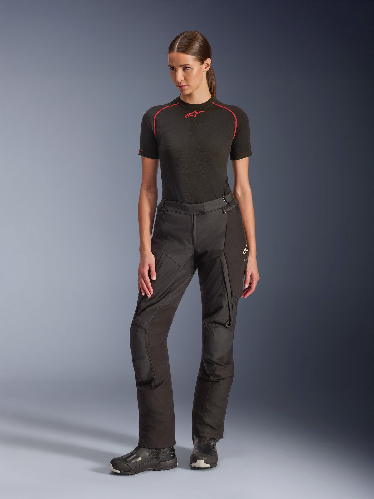 Alpinestars Stella Andes V4 Drystar® Hose, Damen-Adventure-Motorradhose, Schwarz, getragen von einem Model mit einem schwarzen kurzärmeligen Baselayer und schwarzen Motorradstiefeln, mit verstärkten Knien und Cargotaschen, ergonomisches Design für Touren bei jedem Wetter.