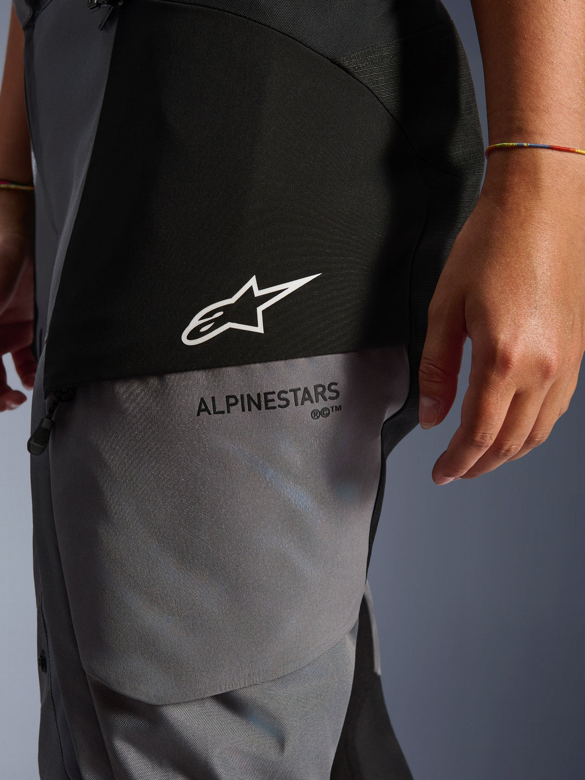 Woman Stella Andes V4 Drystar® Pants, Black and Dark Gray, close-up of the upper thigh showing white star logo and black Alpinestars branding, durable adventure touring textile material
