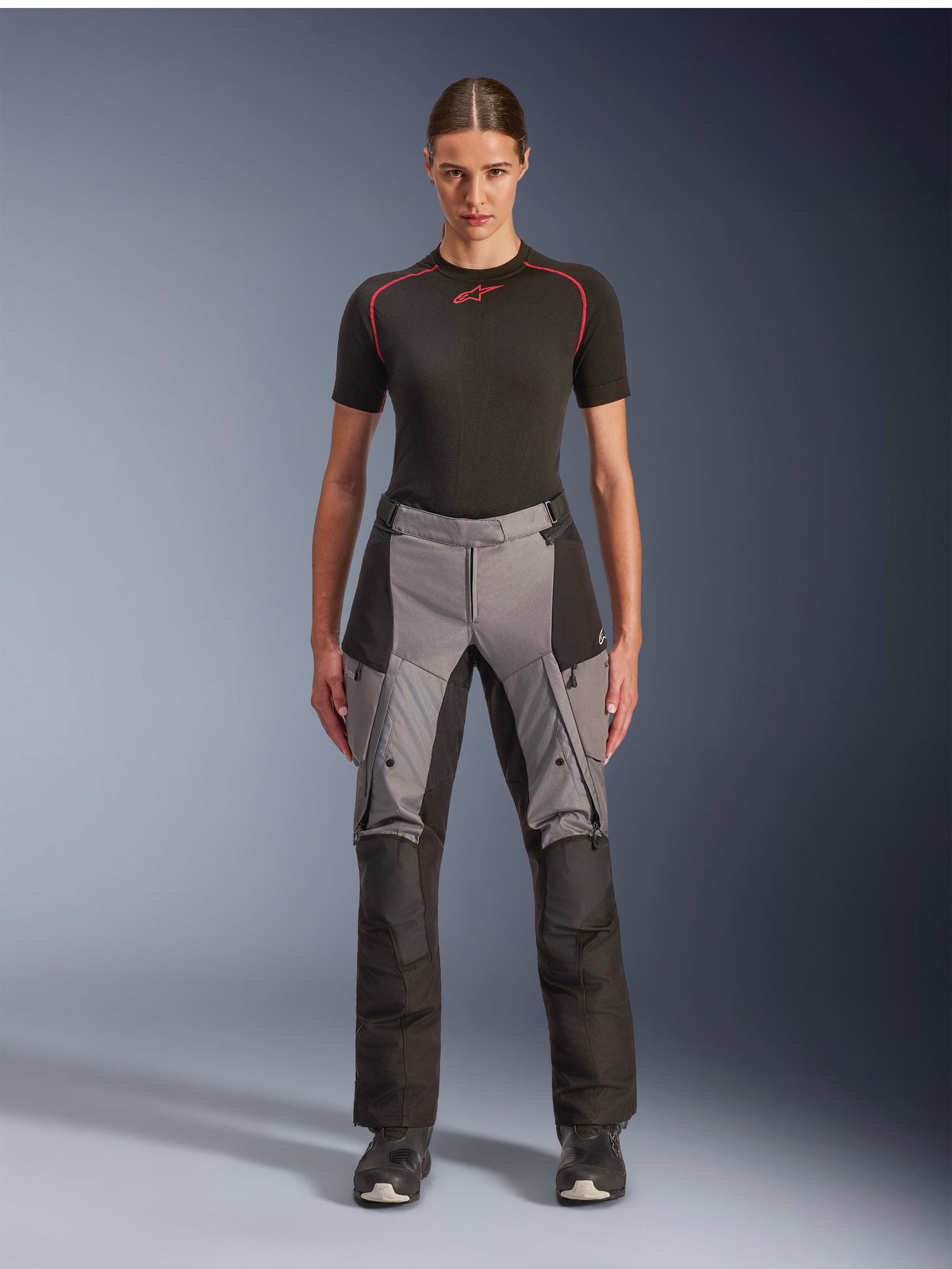 Alpinestars Stella Andes V4 Drystar Pants, Women's Adventure Touring Motorcycle Pants, Black and Dark Gray, worn by a female model with a black base layer and motorcycle boots, featuring reinforced textile panels and cargo pockets for adventure riding