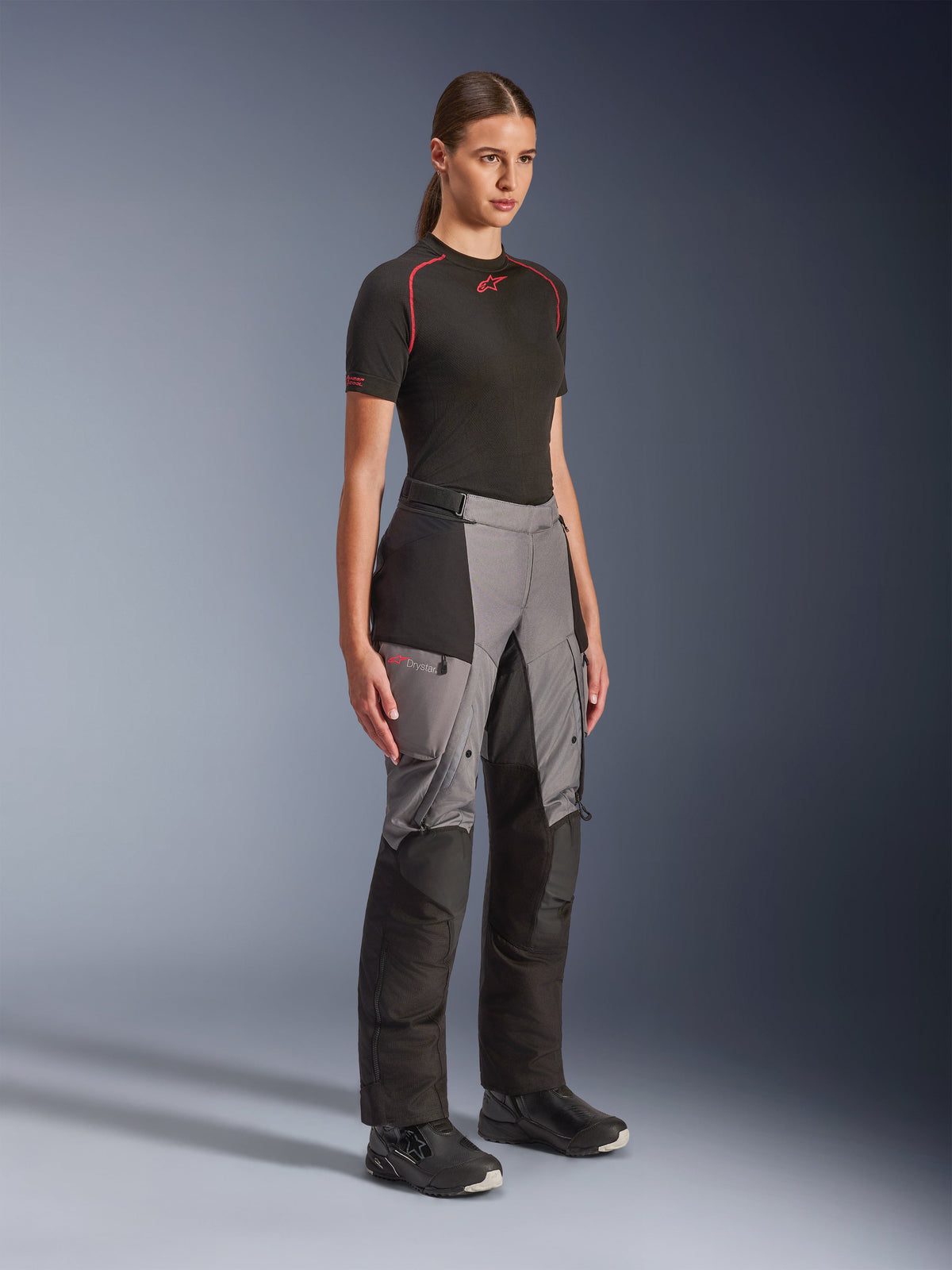 Alpinestars Stella Andes V4 Drystar® Pants, Women's Adventure Motorcycle Pants, Black and Dark Gray, worn by a model with a black Alpinestars base layer and black boots, featuring reinforced panels, red Drystar logo, and cargo pockets.