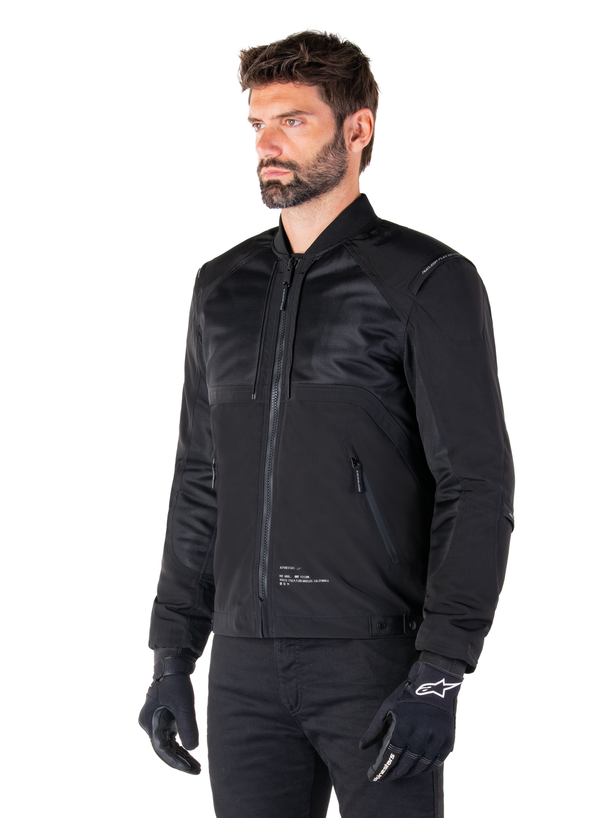 Alpinestars Mootant Waterproof Parka, modular black motorcycle jacket shown in its bomber configuration with mesh upper body panels and a ribbed collar, worn by a model with black riding gloves and pants, urban contemporary streetwear style.