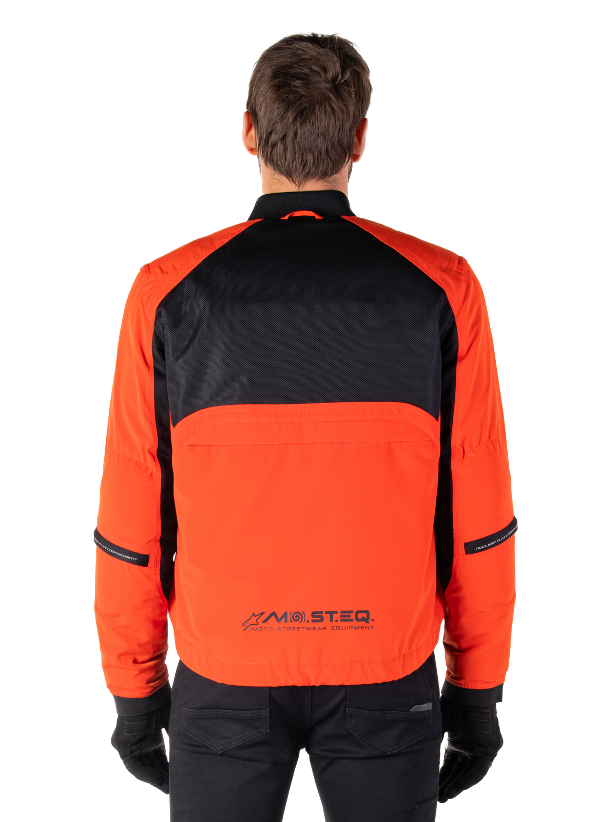 Alpinestars Mootant Waterproof Parka, Motorcycle Jacket, Spicy Orange and Black, Rear View, featuring black mesh upper back and orange lower panel with MO.ST.EQ. logo, worn with black pants and gloves