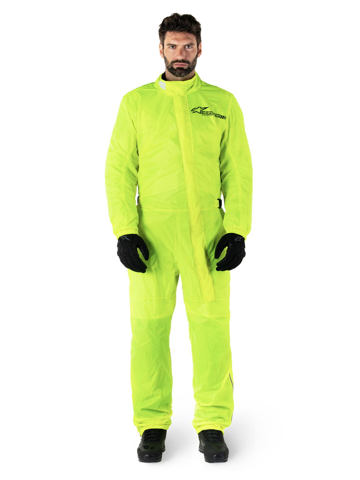 Alpinestars Hurricane Rain V2 Anzug, Motorrad-Regenanzug, Gelb Fluo, männliches Model in Ganzkörperschutz mit schwarzen Handschuhen und Stiefeln, hochgeschlossener Kragen mit vorderer Windschutzleiste, reflektierendes Logo auf der Brust, gut sichtbare wasserdichte Ausrüstung