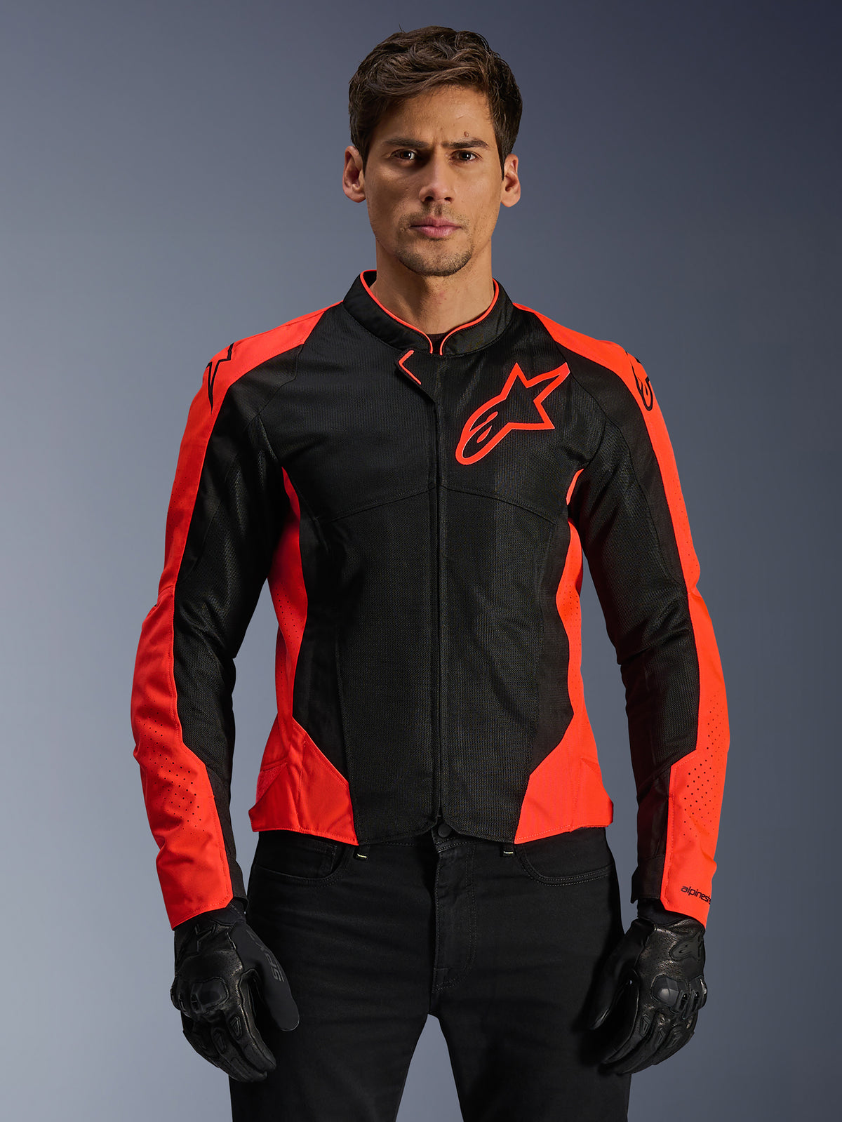 Alpinestars Viper Air V4 Jacke, Motorrad-Rennjacke, Fluo-Rot und Schwarz, getragen von einem Modell mit schwarzen Handschuhen, Tech-Mesh-Einsätze für Belüftung, sportliches Design mit Alpinestars-Sternlogo auf der Brust