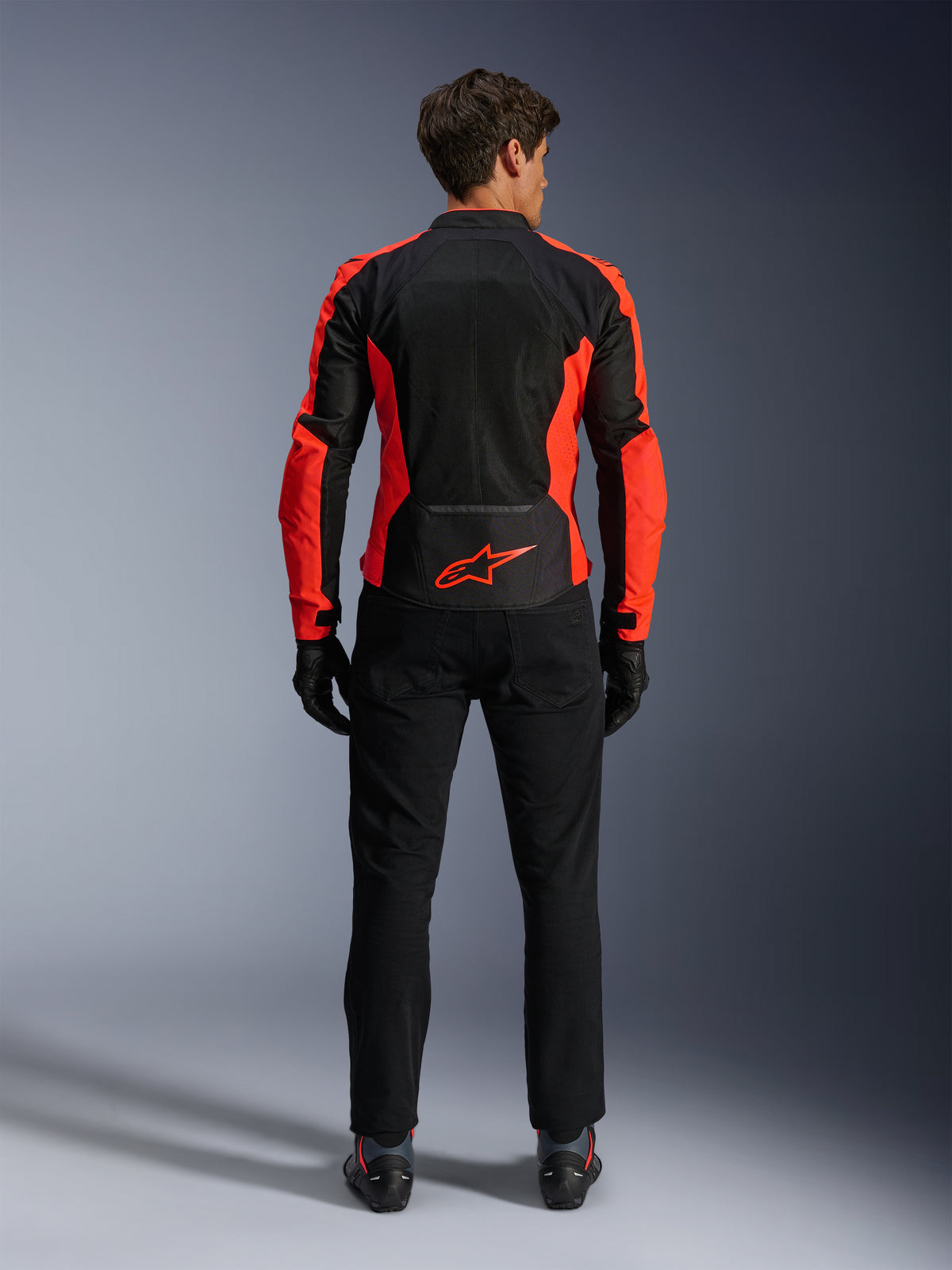 Alpinestars Viper Air V4 Jacke, Rot Fluo und Schwarz, Rückansicht mit großen Tech-Mesh-Einsätzen und leuchtend roten fluoreszierenden Seitenakzenten, rotes Alpinestars-Logo auf dem unteren Rücken, getragen mit schwarzen Motorradhosen und Handschuhen.