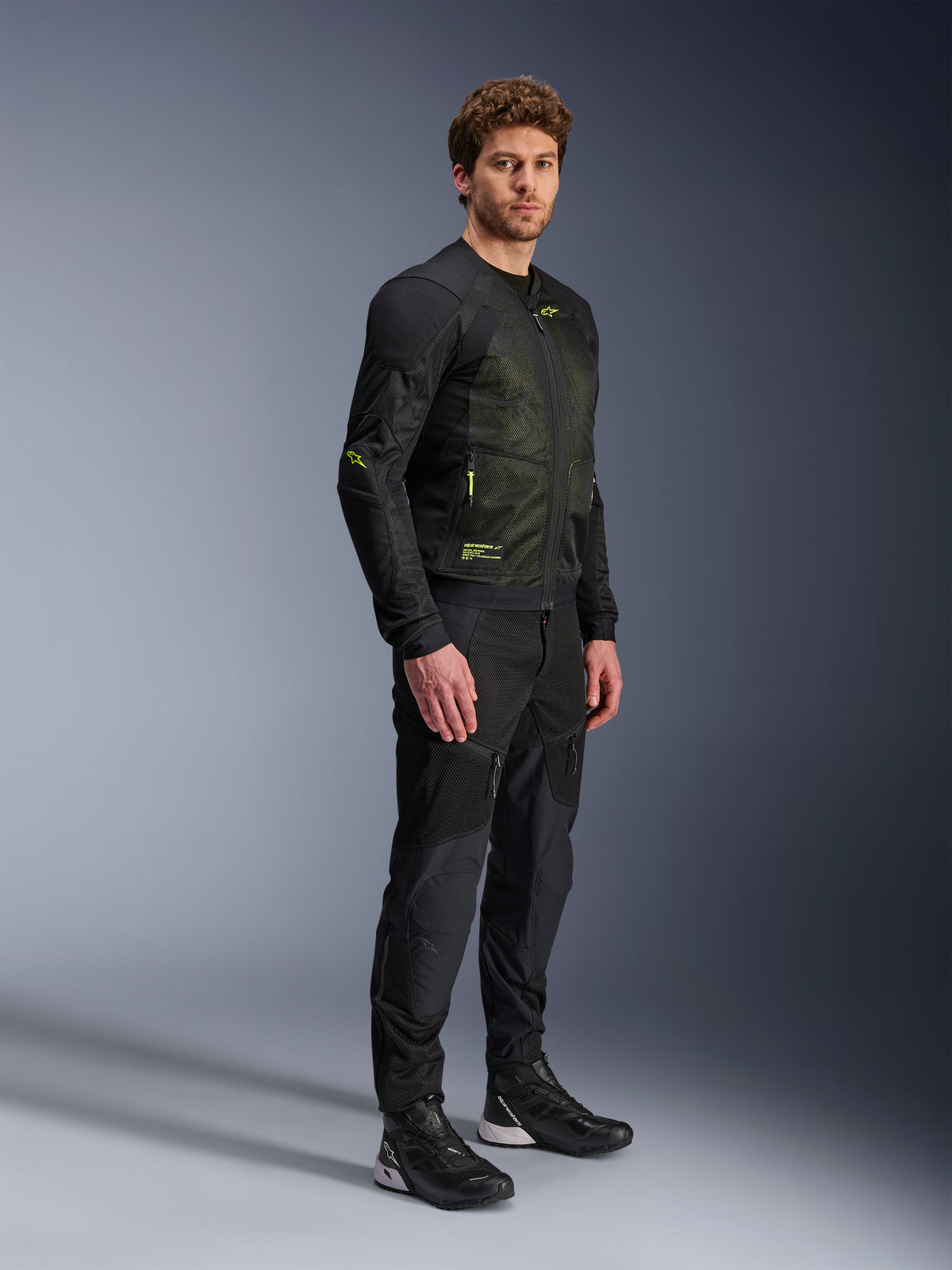 Alpinestars Troop-Air Jacket, Motorcycle Mesh Jacket, Black and Yellow Fluo, worn by a model with matching black pants and riding shoes, features high-airflow mesh construction with yellow fluorescent accents on the chest and sleeves, lightweight technical design for road riding