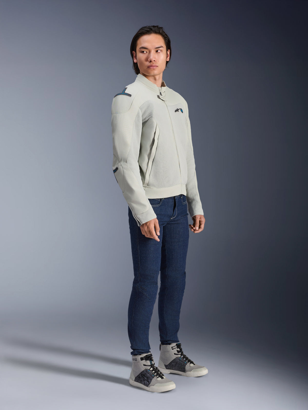 Alpinestars Circal-1 Air Jacket in Metal Gray and Methyl Blue, worn by a model with dark blue jeans and gray sneakers, urban summer motorcycle jacket featuring large mesh airflow panels and a minimalist design.
