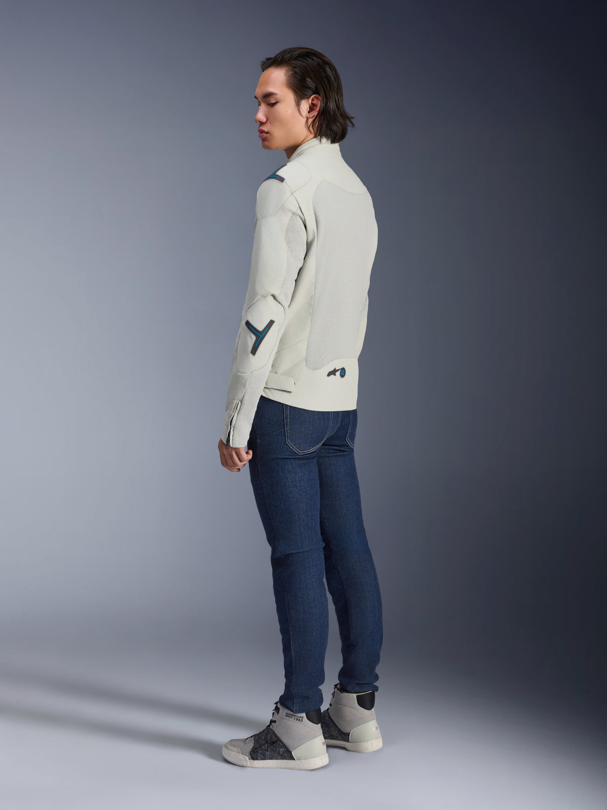 Alpinestars Circal-1 Air Jacket, Urban Motorcycle Jacket, Metal Gray with Methyl Blue accents, worn by a model from a rear three-quarter view with dark blue jeans and gray high-top sneakers, featuring mesh panels and a minimalist design