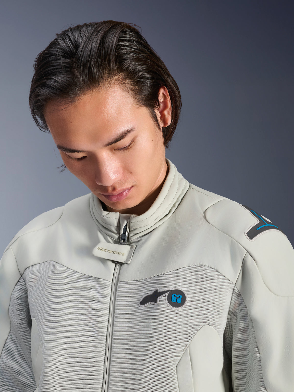 Male model wearing the Alpinestars Circal-1 Air Jacket in Metal Gray with Methyl Blue accents, close-up view highlighting the collar, mesh chest panels, and minimalist logo branding, sustainable urban motorcycle gear.