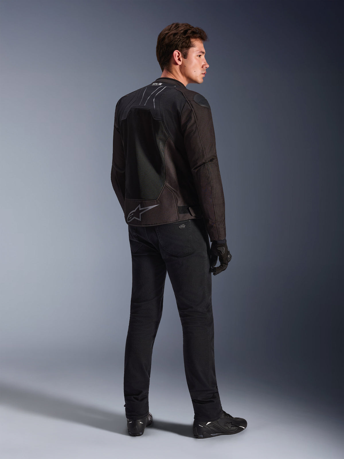 Alpinestars SMX Air Jacke in Schwarz Anthrazit, Rückansicht am Model, mit Tech-Air® Ready-Branding am Kragen und Astar-Logo am unteren Rücken, getragen mit schwarzer Motorradhose und Schuhen.