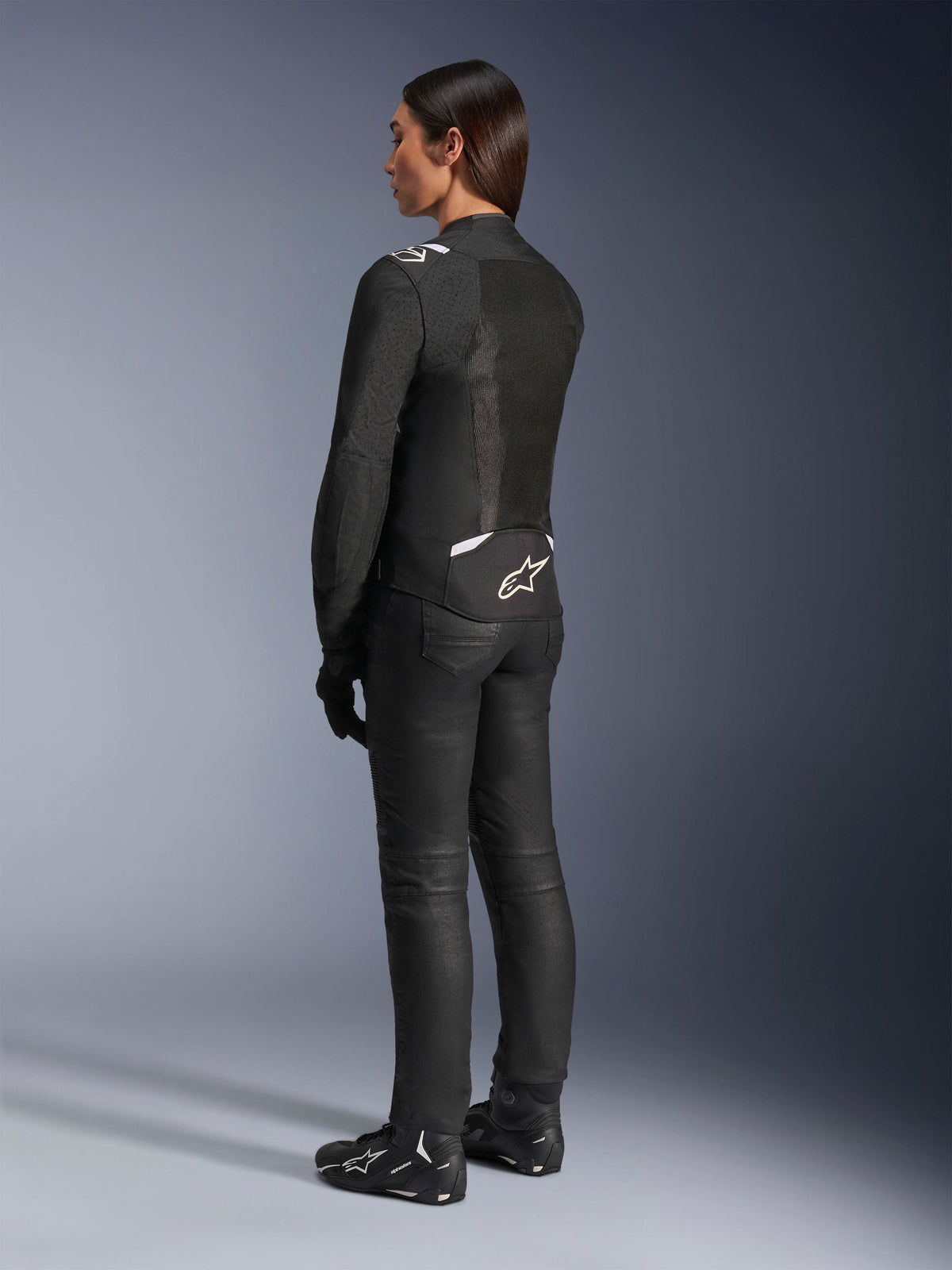 Alpinestars Stella T-SPS Air v2 Jacke, Schwarz und Weiß, Rückansicht mit Mesh-Einsätzen und Logo am unteren Rücken, kombiniert mit schwarzer Motorradhose und Motorradschuhen, sportliche Textil-Straßenausrüstung für Damen
