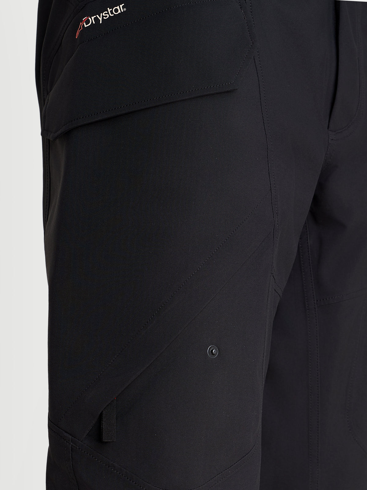 Alpinestars Juggernaut V 2 Drystar Hose, urbane wasserdichte Herren-Motorradhose in Schwarz, Nahaufnahme mit Fokus auf die seitliche Cargotasche und Drystar-Branding