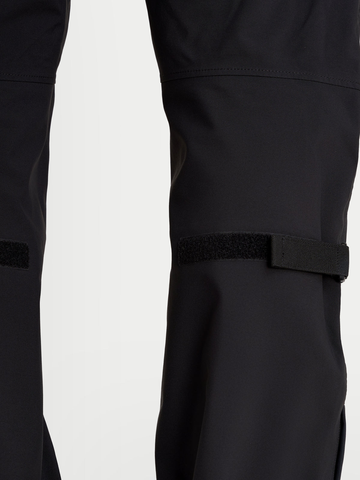 Alpinestars Juggernaut V 2 Drystar Hose, urbane wasserdichte Herren-Motorradhose in Schwarz, Nahaufnahme der Unterschenkelverstellungen und der technischen Textilkonstruktion