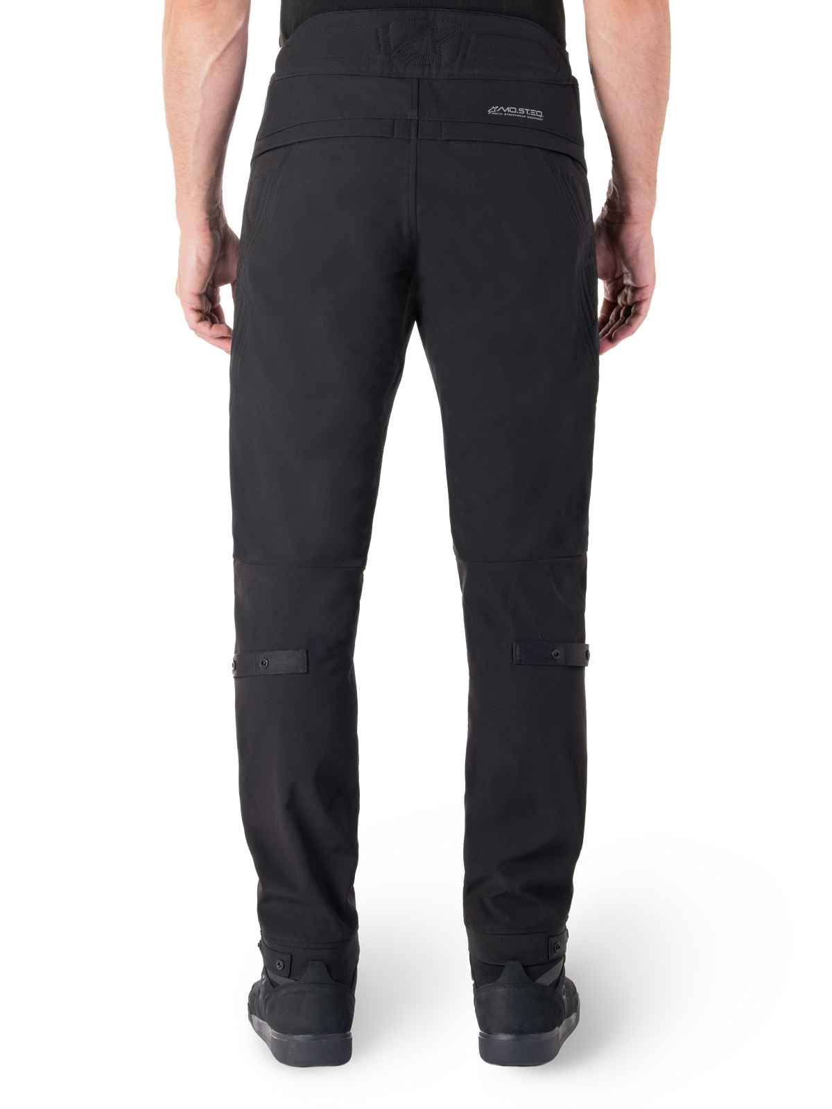 Alpinestars Alden Hose, schwarze Urban-Motorradhose, Rückansicht, mit reflektierender MO.ST.EQ. Wortmarke auf der Rückenpasse, schmale Passform unterhalb des Knies sowie Druckknopf-Volumenregulierer an Waden und Bündchen, von Streetwear inspiriertes technisches Textildesign.