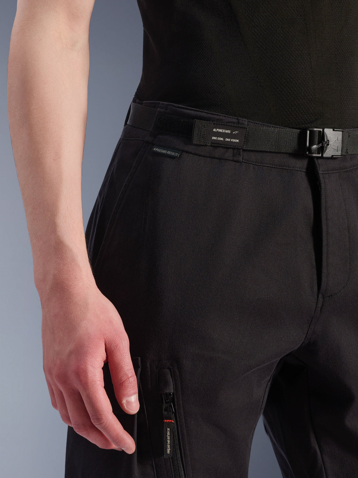 Alpinestars Flex-AST Cargo Pants, Urban Motorcycle Pants, Black, close-up view of waist and side pocket, featuring an integrated belt with Alpinestars branding, buckle closure, and a zippered pocket with a branded puller, technical textile construction for urban riding