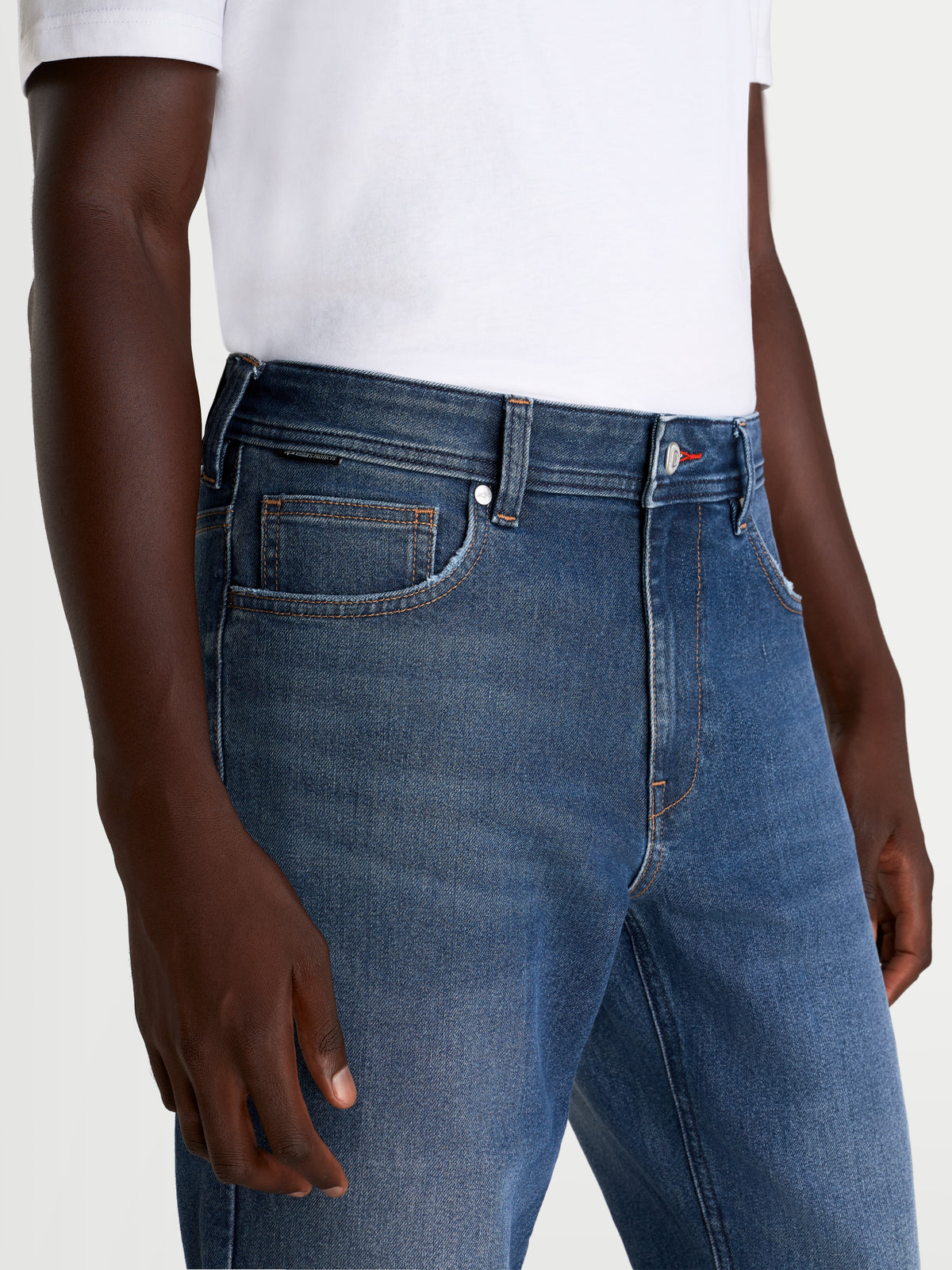 Alpinestars Flex-AST 8 Denim Pants, men's urban motorcycle riding jeans in medium blue, close-up view focusing on the waist and front pocket construction, worn by a model.