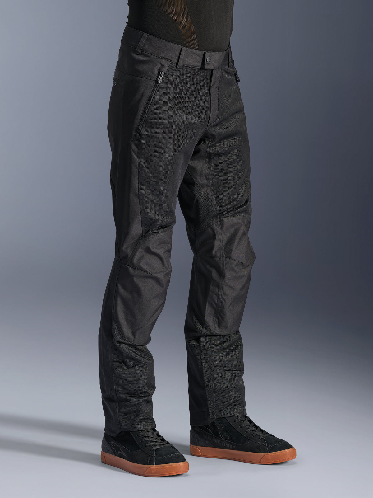 Alpinestars C-1 Air Hose, urbane Motorradhose, Schwarz, mit atmungsaktiven Tech-Mesh-Einsätzen und Poly-Gewebe-Konstruktion, getragen mit schwarzen Sneakern, klares und funktionales Design für Fahrten in der Stadt.