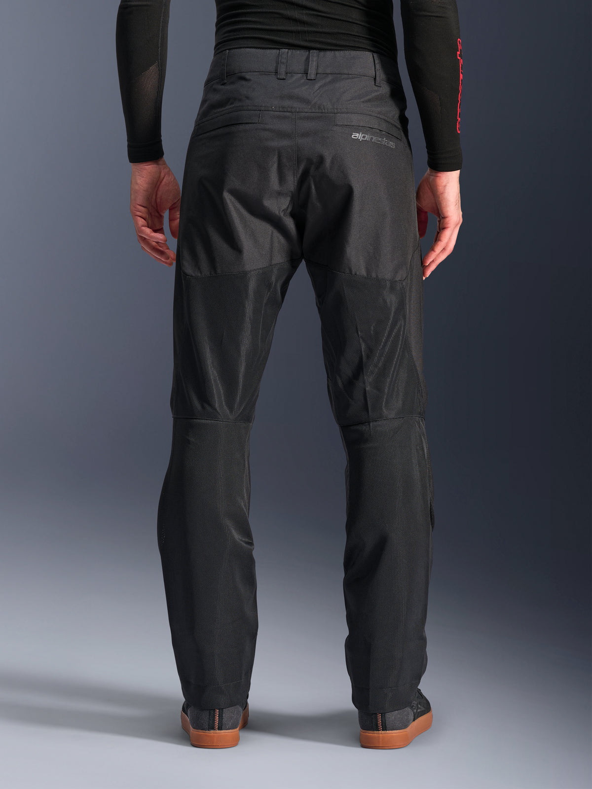 Alpinestars C-1 Air Hose, Rückansicht, Schwarz, urbane Textil-Motorradhose mit großen Tech-Mesh-Einsätzen an der Beinrückseite zur Belüftung, schlichtes Design mit dezentem Branding, getragen mit einem schwarzen Base-Layer und lässigen Fahrerschuhen.