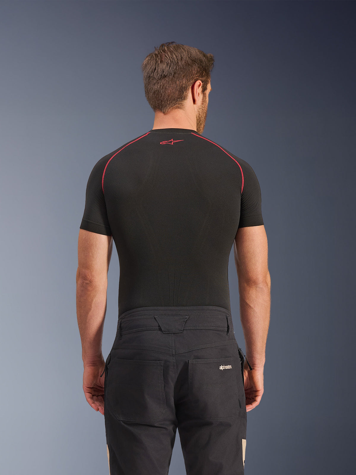Alpinestars Flex-AST Canvas Pants in Black Aluminum, rear view on model, workwear-inspired urban motorcycle pants with logo on back pocket, paired with a black short-sleeve base layer featuring red stitching.