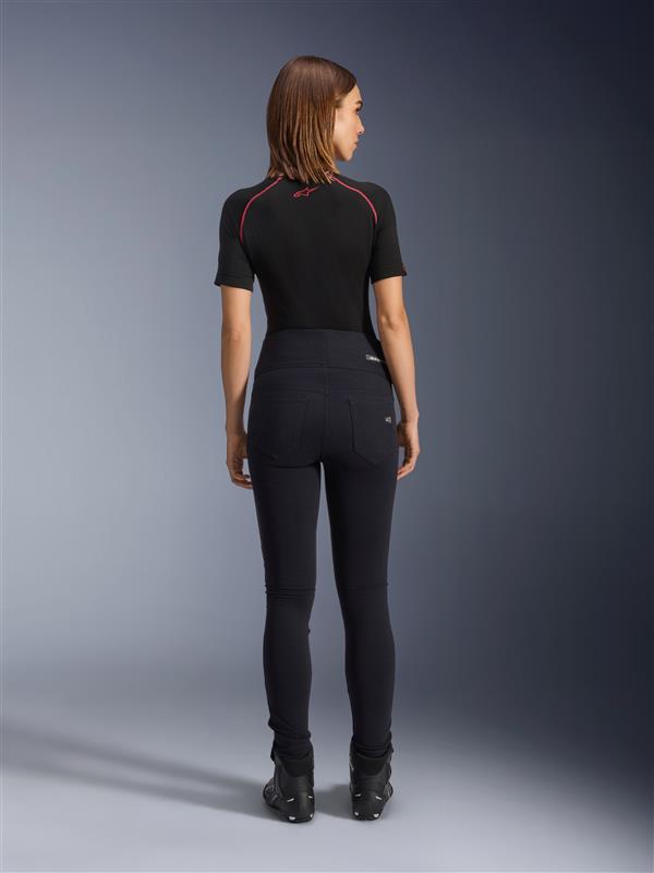 Alpinestars Stella Flex-Ast Leggings, Motorrad-Leggings für Damen, Schwarz, Rückansicht mit hoch taillierter Slim-Fit-Passform, kombiniert mit schwarzem Kurzarm-Oberteil und schwarzen Motorradstiefeln, urbane Fahrausrüstung