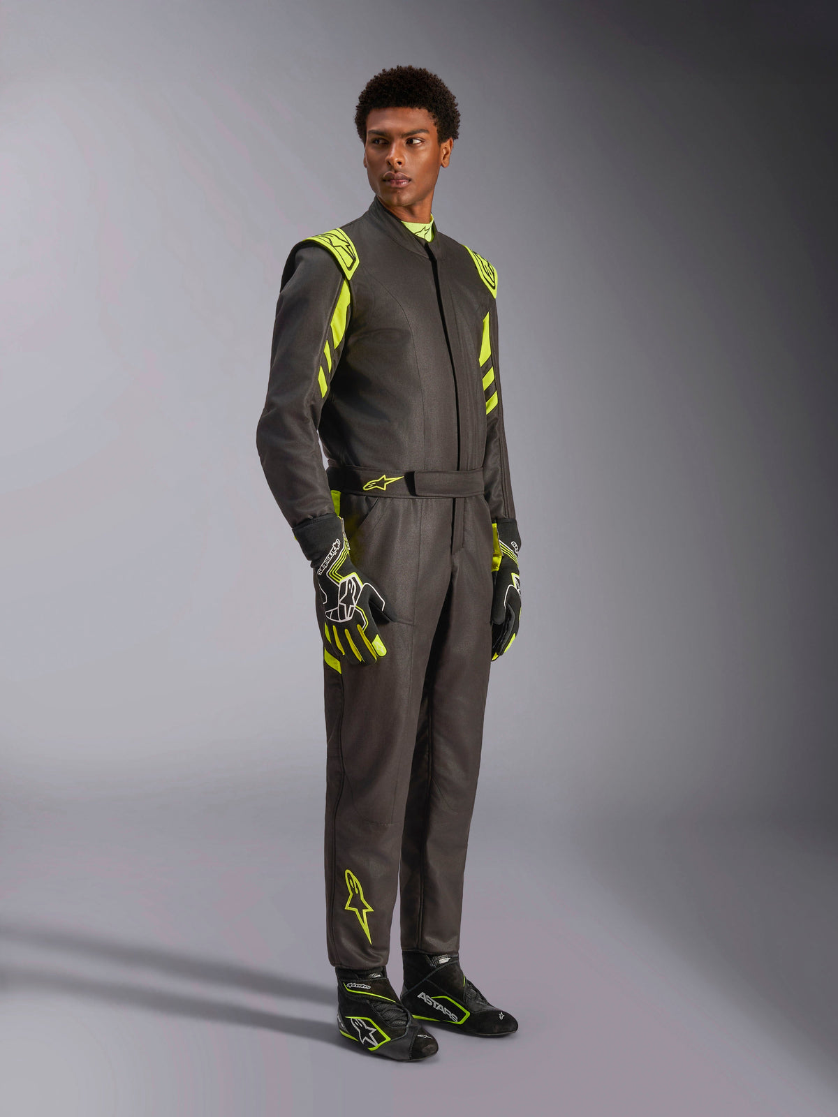 Alpinestars GP Race V3 Suit FIA, Auto Racing Suit, Black and Yellow Fluo, worn by a model with matching racing gloves and boots, featuring vibrant yellow accents on the shoulders and legs, professional motorsport gear