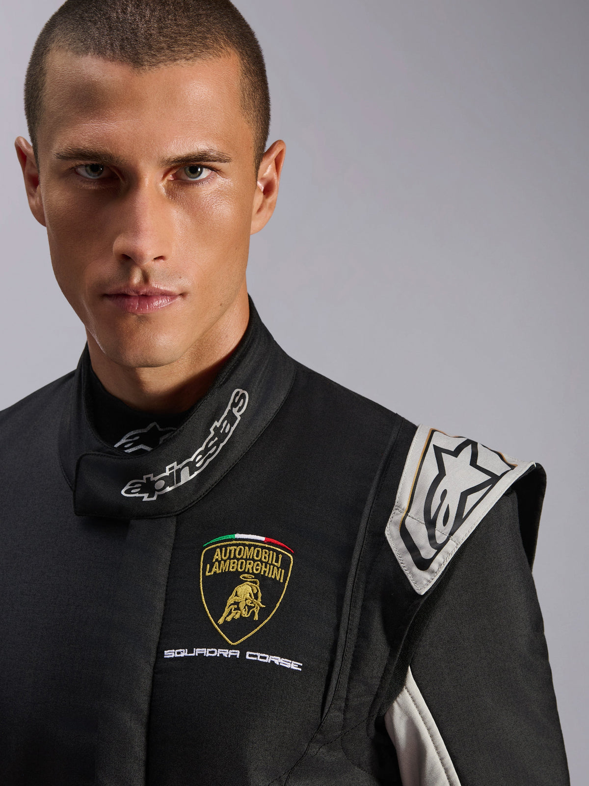 Alpinestars Limited Edition Lamborghini GP Tech V4 Anzug, professioneller Rennanzug, Schwarz mit silbernen und goldenen Akzenten, Nahaufnahme mit Lamborghini Squadra Corse Brustlogo und Alpinestars-Branding am Kragen, erstklassiger Motorsport-Schutz