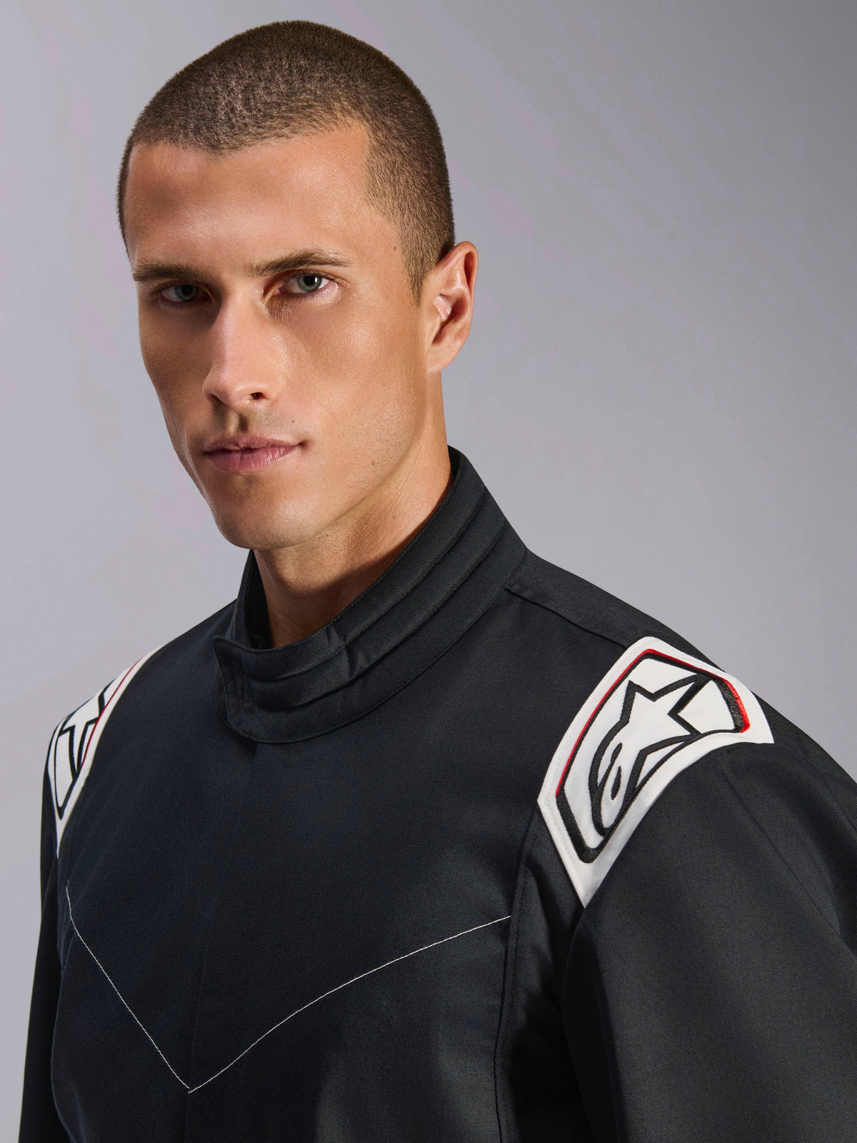 Alpinestars Kart Indoor V2 Anzug, Schwarz, Nahaufnahme von Schultern und Kragen, weiße Schulterklappen mit schwarzem Astars-Logo, ergonomisches Kragendesign, strapazierfähige Poly-Baumwoll-Twill-Konstruktion für Indoor-Karting
