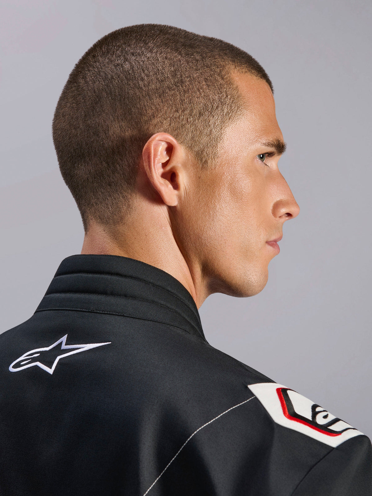 Alpinestars Kart Indoor V2 Anzug, Schwarz, Nahaufnahme des ergonomischen Kragens und des von der Formel 1 abgeleiteten Schulterdesigns, mit weißem Alpinestars-Logo und vom Rennsport inspirierten Details auf strapazierfähigem Twill-Gewebe
