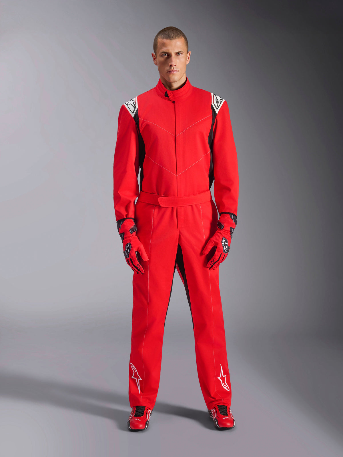 Alpinestars Kart Indoor V2 Anzug, Rot, einteiliger Kart-Anzug getragen mit passenden roten Handschuhen und Rennschuhen, mit weißen Logos auf Schultern und Beinen, schwarze Akzente, stromlinienförmiges Design für den Freizeit-Rennsport
