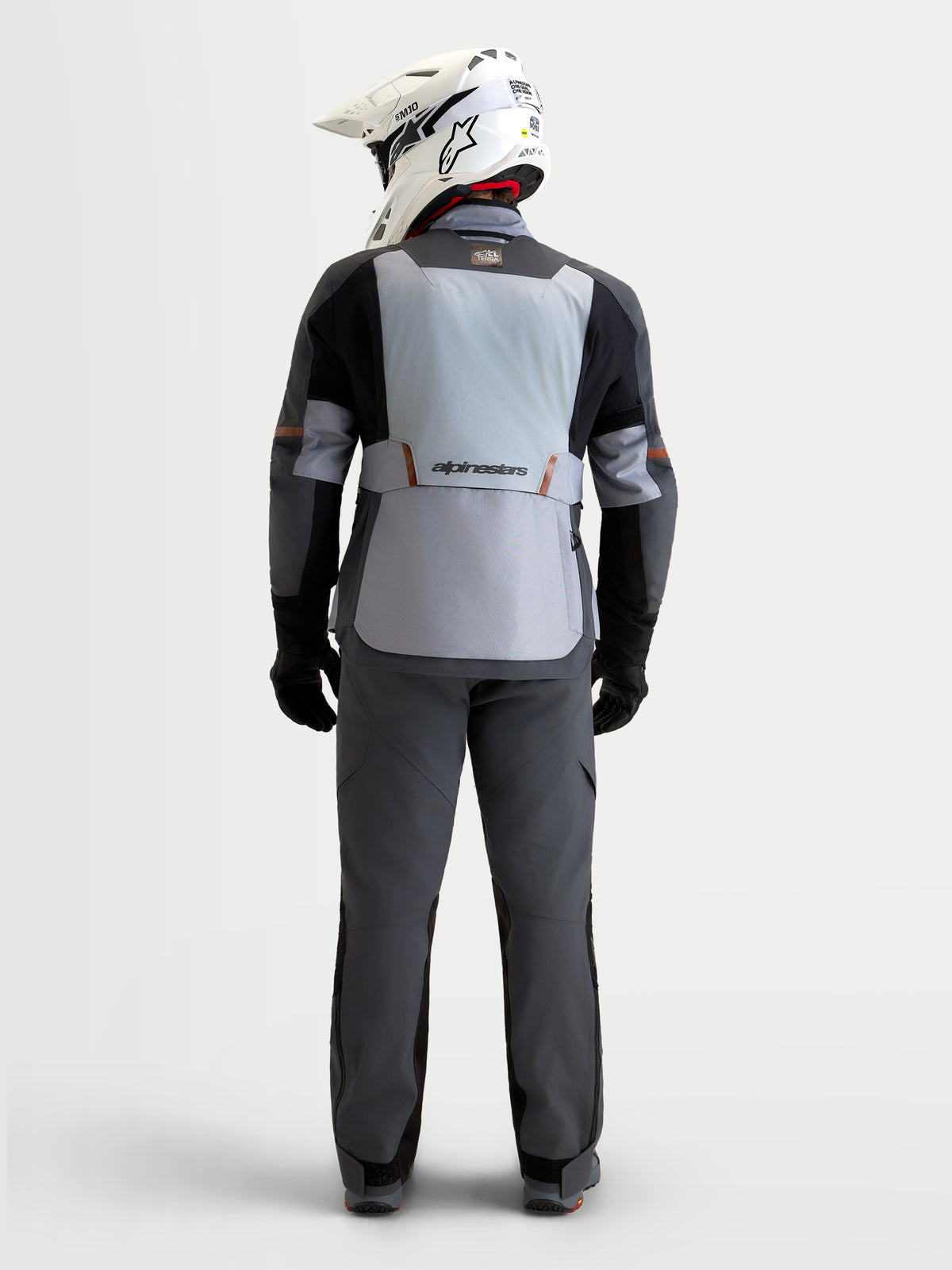 Alpinestars St-7 V2 2L Gore-Tex Jacket, Men's Adventure Touring Motorcycle Jacket, Mid Gray, Deep Gray and Black, rear view showing a rider wearing the waterproof textile riding jacket, white helmet, and matching touring pants
