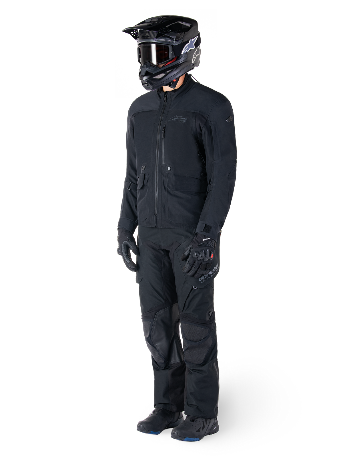 Motorradfahrer in der Alpinestars St-7 Prime GORE-TEX Jacke in Schwarz, abgestimmtes Adventure-Touring-Outfit mit passender schwarzer Hose, schwarzem Helm mit Brille und Handschuhen, schlankes und funktionales Design für Allwetter-Performance.