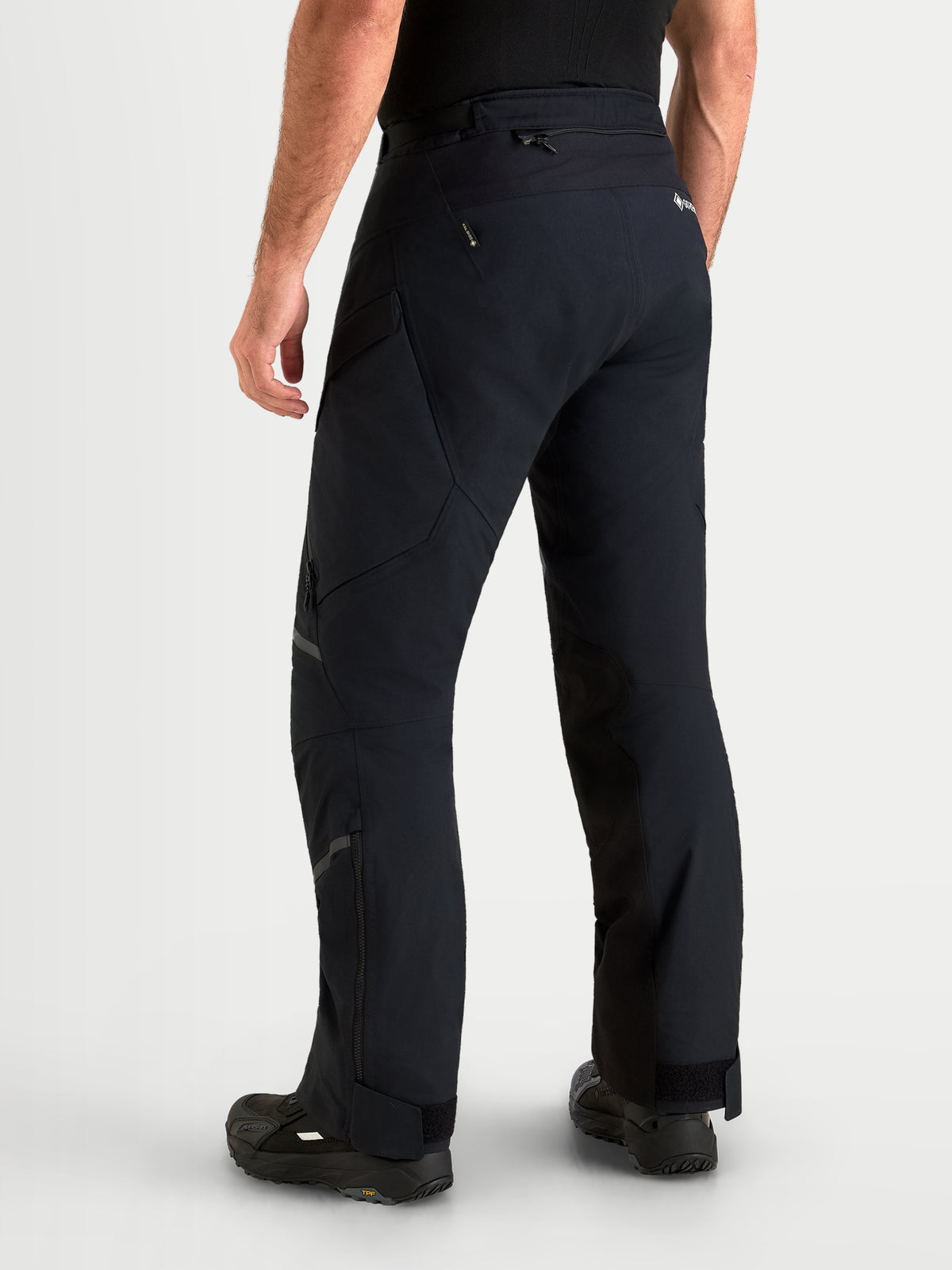 Alpinestars St-7 V2 2L Gore-Tex® Pants, men's adventure touring motorcycle pants in black, rear three-quarter view on a model showing waterproof textile construction and lower leg zippers.