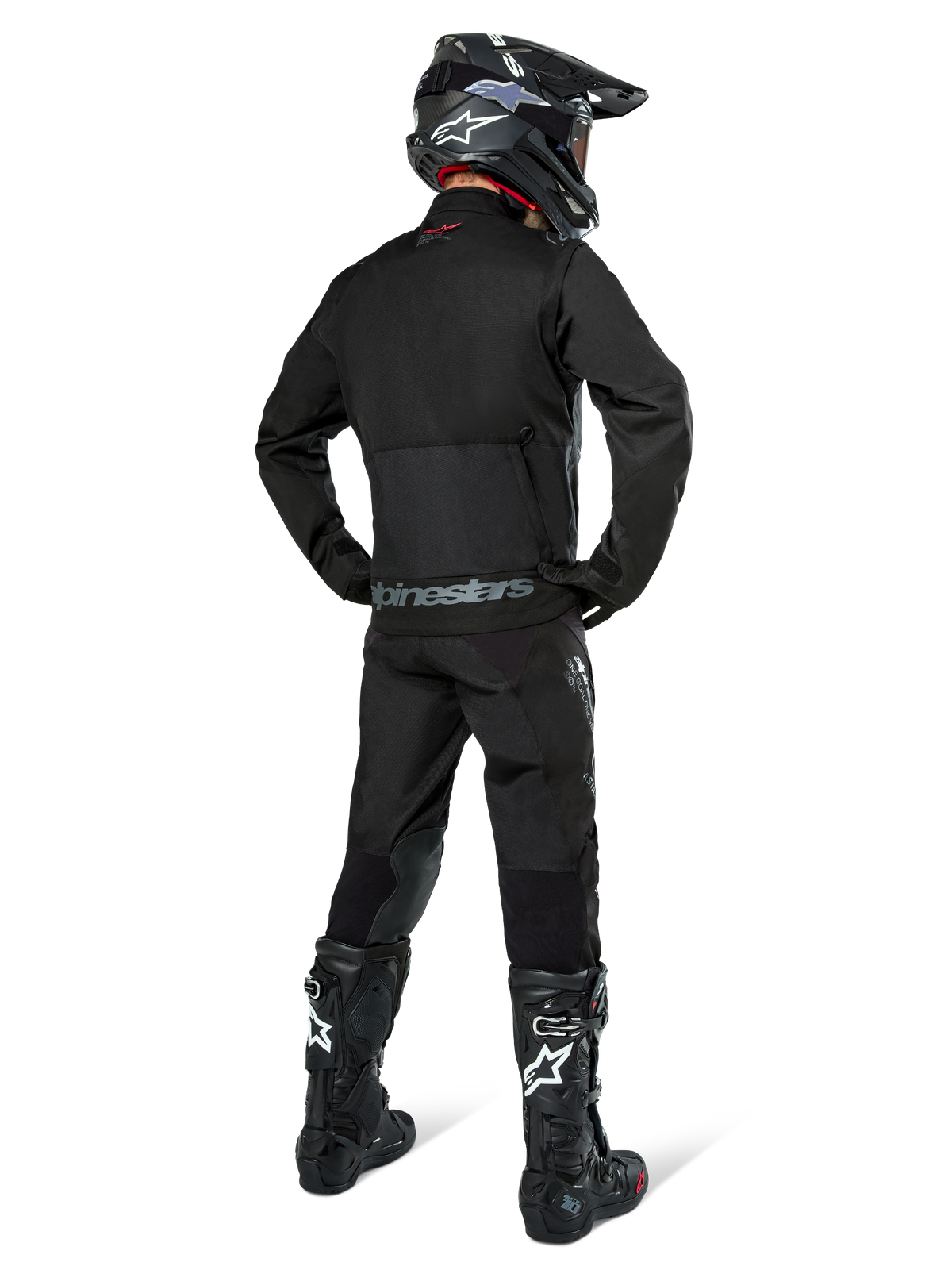 Alpinestars Pro-Dura Jacke, schwarze Offroad-Enduro-Jacke, Rückansicht getragen mit passender Hose und schwarzen Tech 10 Stiefeln, mit markantem Alpinestars-Branding am unteren Rücken, robuste Textilkonstruktion für aggressives Trail-Fahren