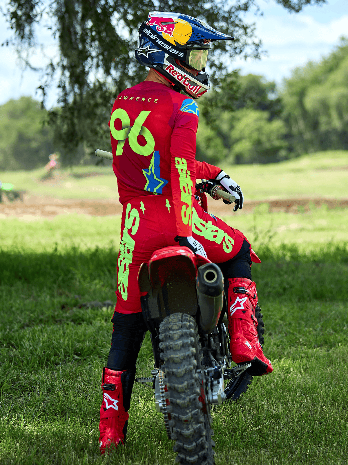 Motocross-Fahrer auf einem roten Dirtbike, Alpinestars 2025 Supertech Maker Hose in Bright Red und Yellow Fluo, passendes rotes Trikot mit „96“ und „LAWRENCE“ auf dem Rücken, rote Rennstiefel und ein Helm mit Red Bull-Branding, professionelles Offroad-Rennausrüstungsset