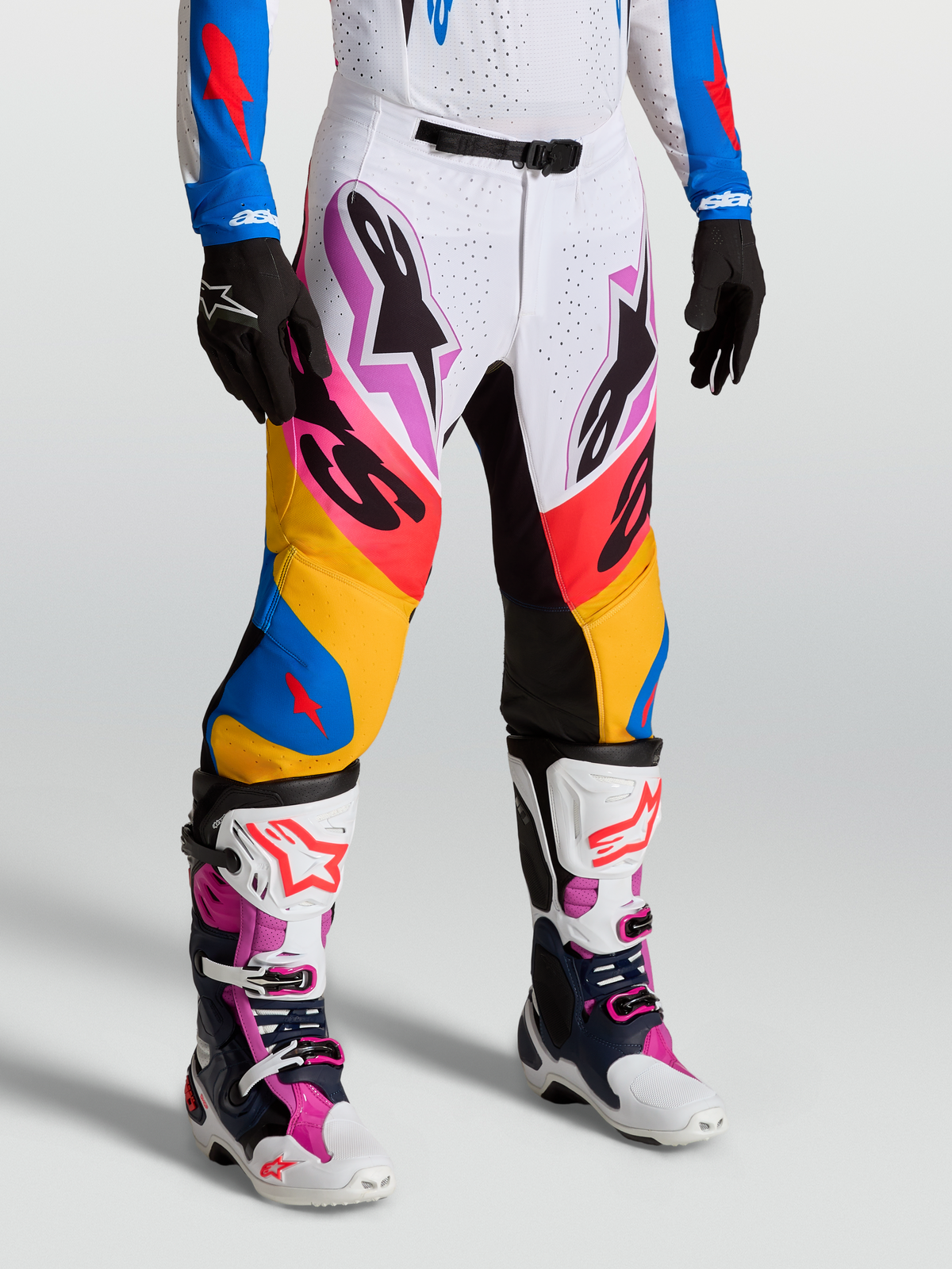 Alpinestars Supertech Dyna Pants in white and blithe blue, premium motocross racing pants on-model with stretch rip-stop fabric and goat leather knee panels.