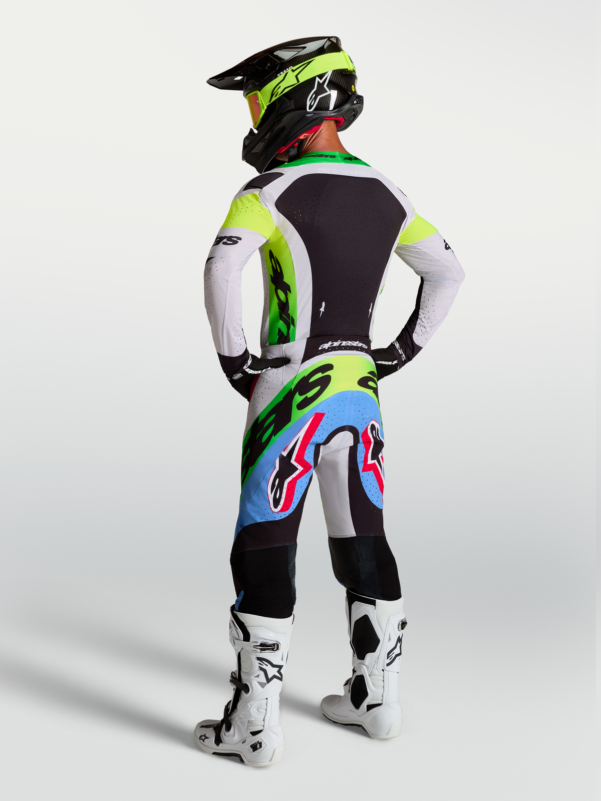 Alpinestars Supertech Dyna motocross gear in Green Fluo, Black, and Light Lilac, with racing pants and jersey, rear view.