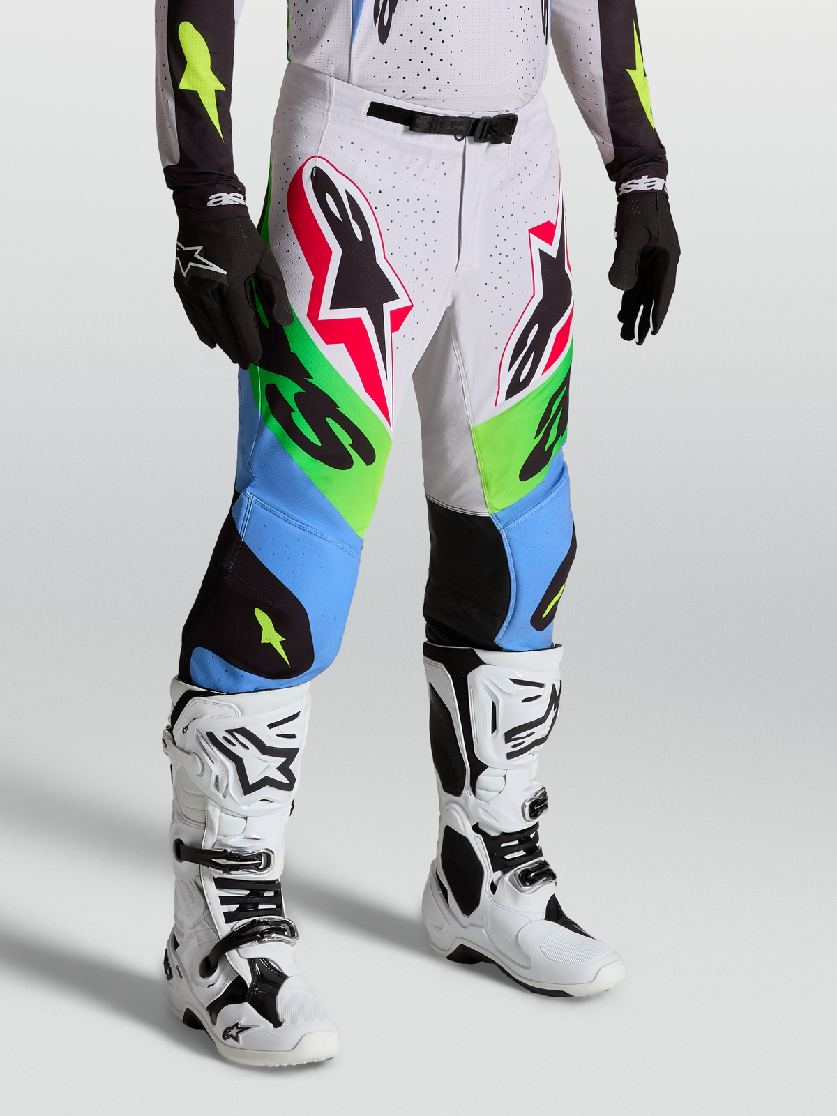Alpinestars Supertech Dyna Pants in green and blue, professional motocross racing pants on-model with white boots and black gloves.