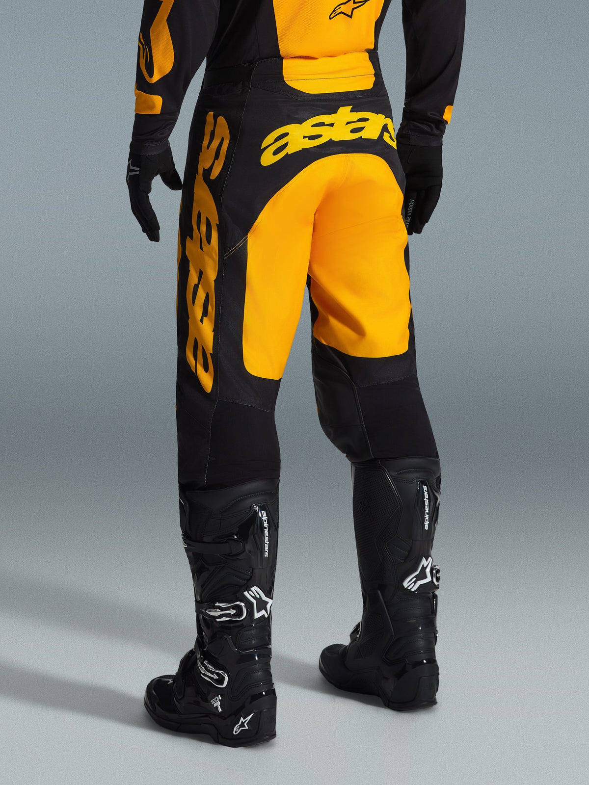 Alpinestars 2026 Racer Riway Hose, Motocross-Hose, Gelb und Schwarz, Rückansicht mit auffälligem gelbem Astars-Branding auf dem Gesäß und am Bein, kombiniert mit schwarzen Motocross-Stiefeln und Handschuhen