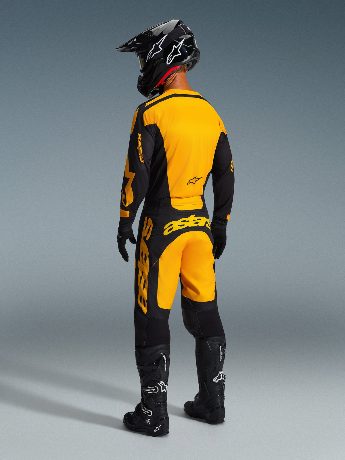 Rückansicht eines Motocross-Fahrers in der Alpinestars 2026 Racer Riway Hose in Gelb und Schwarz, passendes Trikot, schwarzer Helm und schwarze Stiefel, abgestimmtes Rennbekleidungsset für Offroad-Performance
