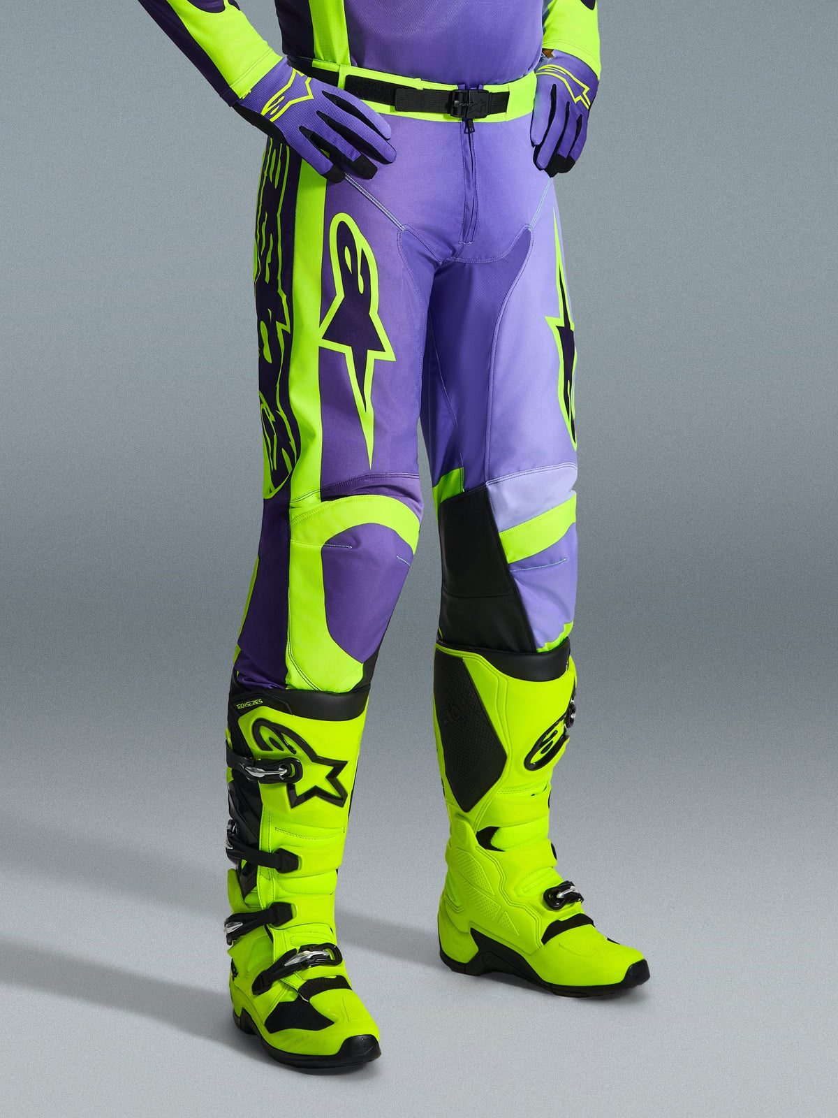 Alpinestars 2026 Racer Portl Hose, Motocross-Hose in Lila und Neongelb, getragen von einem Fahrer mit passenden neongelben Stiefeln und lila Handschuhen, markantes Alpinestars-Branding, ergonomisches Design für Offroad-Performance
