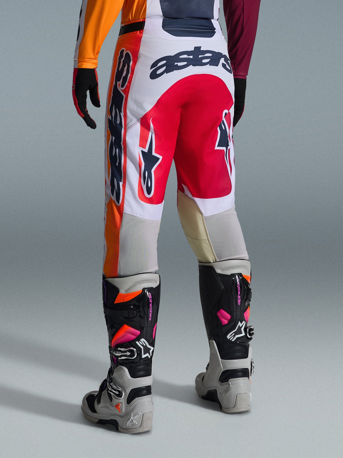 Alpinestars 2026 Racer Portl Hose, Motocross-Hose, Rot, Hellgrau und Dunkelgrau, Rückansicht mit markanten Branding- und Logo-Details, kombiniert mit abgestimmten Motocross-Stiefeln und Handschuhen, Performance-Ausrüstung für den Offroad-Rennsport