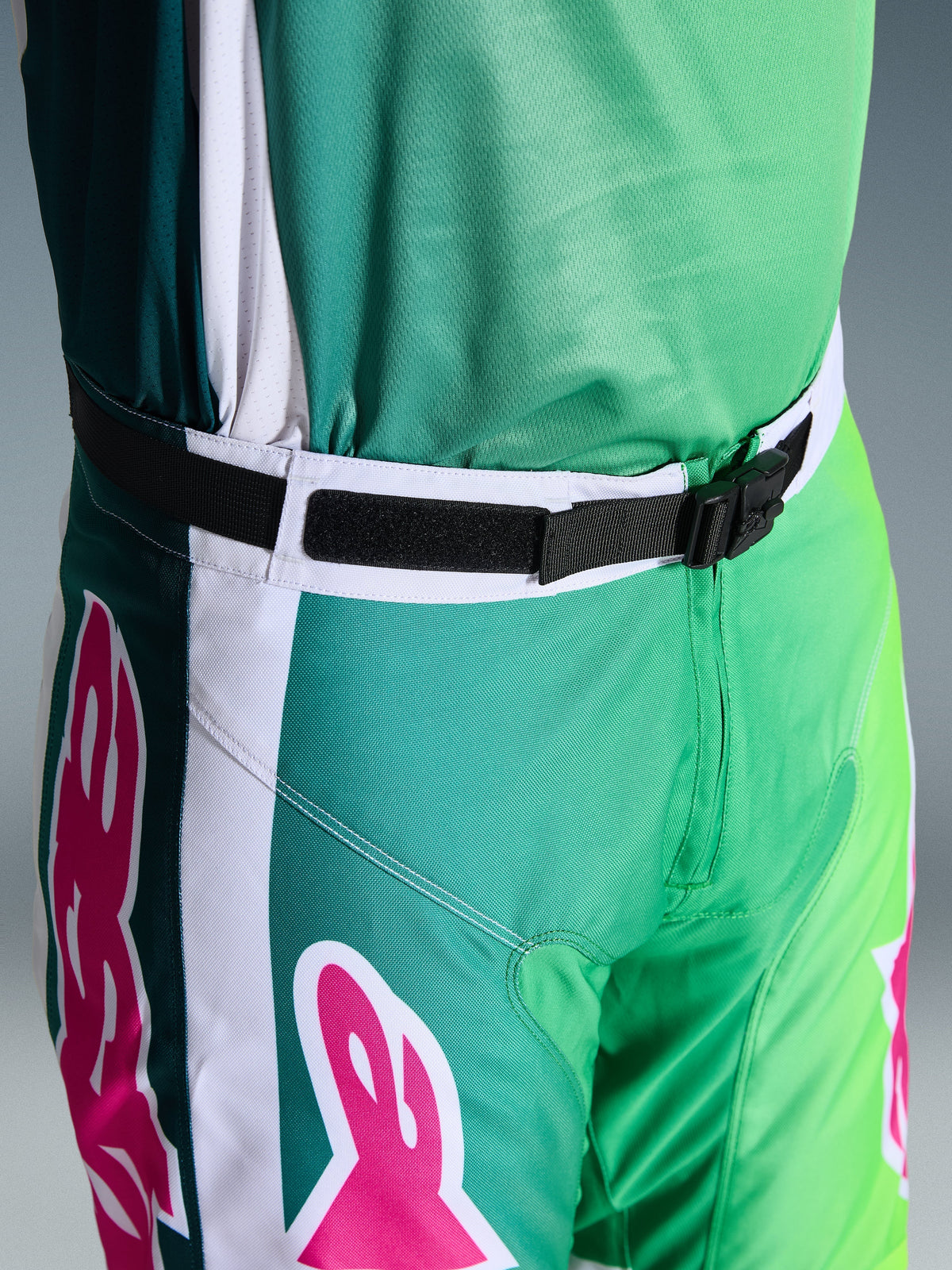 Alpinestars 2026 Racer Portl Hose, Motocross-Hose, Grün, Weiß und Schwarz mit rosa Logo-Akzenten, Nahaufnahme der Taille mit der magnetischen SX2-Schnalle und verstellbarem Verschluss, strapazierfähige Ausrüstung für den Offroad-Rennsport